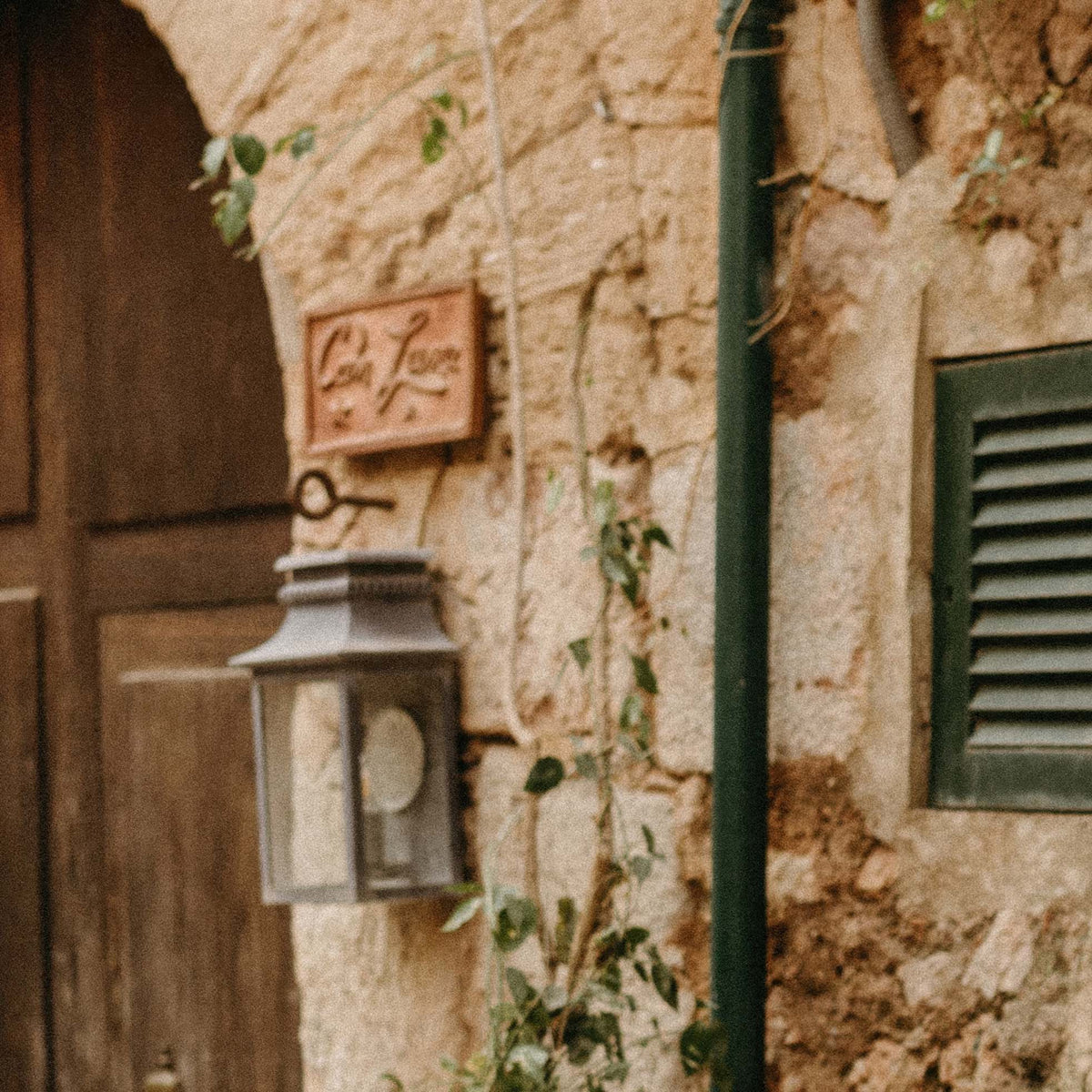 Close-up of vintage-style lantern on a stone wall with a sign above it