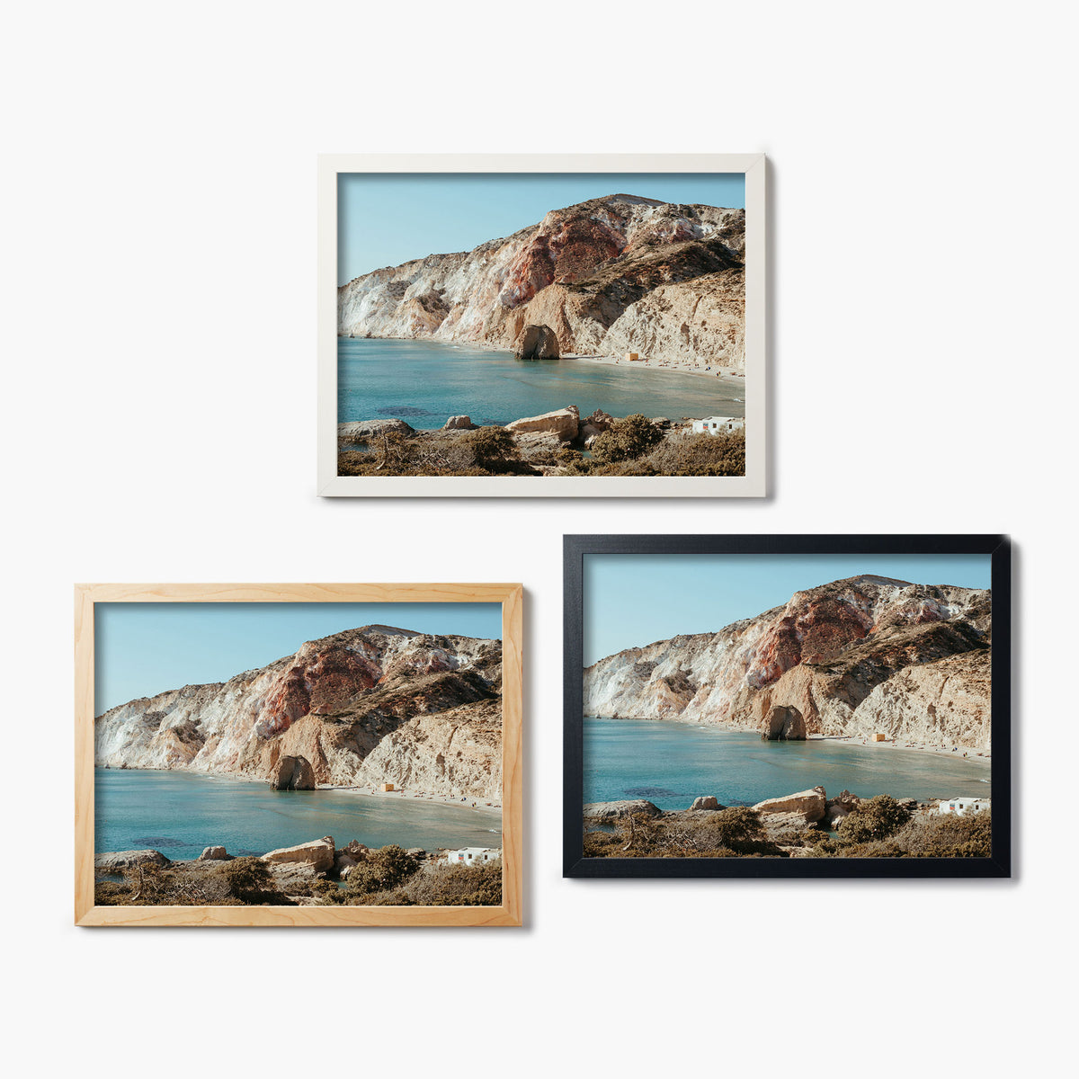 Three framed glass prints of a coastal landscape with mountains and water.