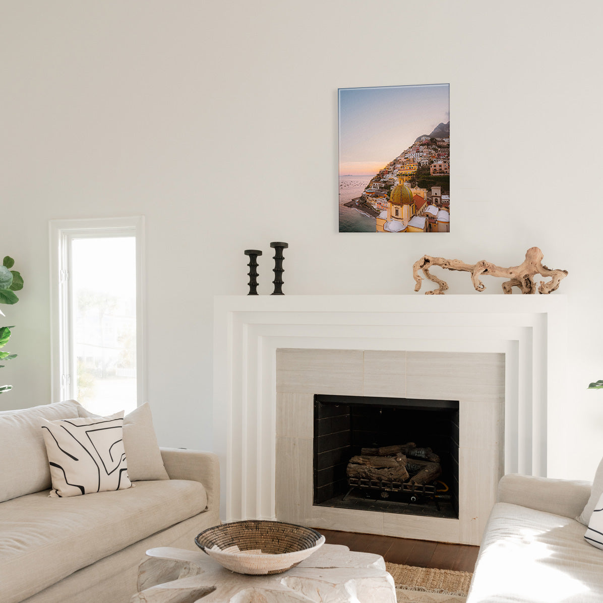Living room with a fireplace and a glass print of a scenic Positano hillside above it