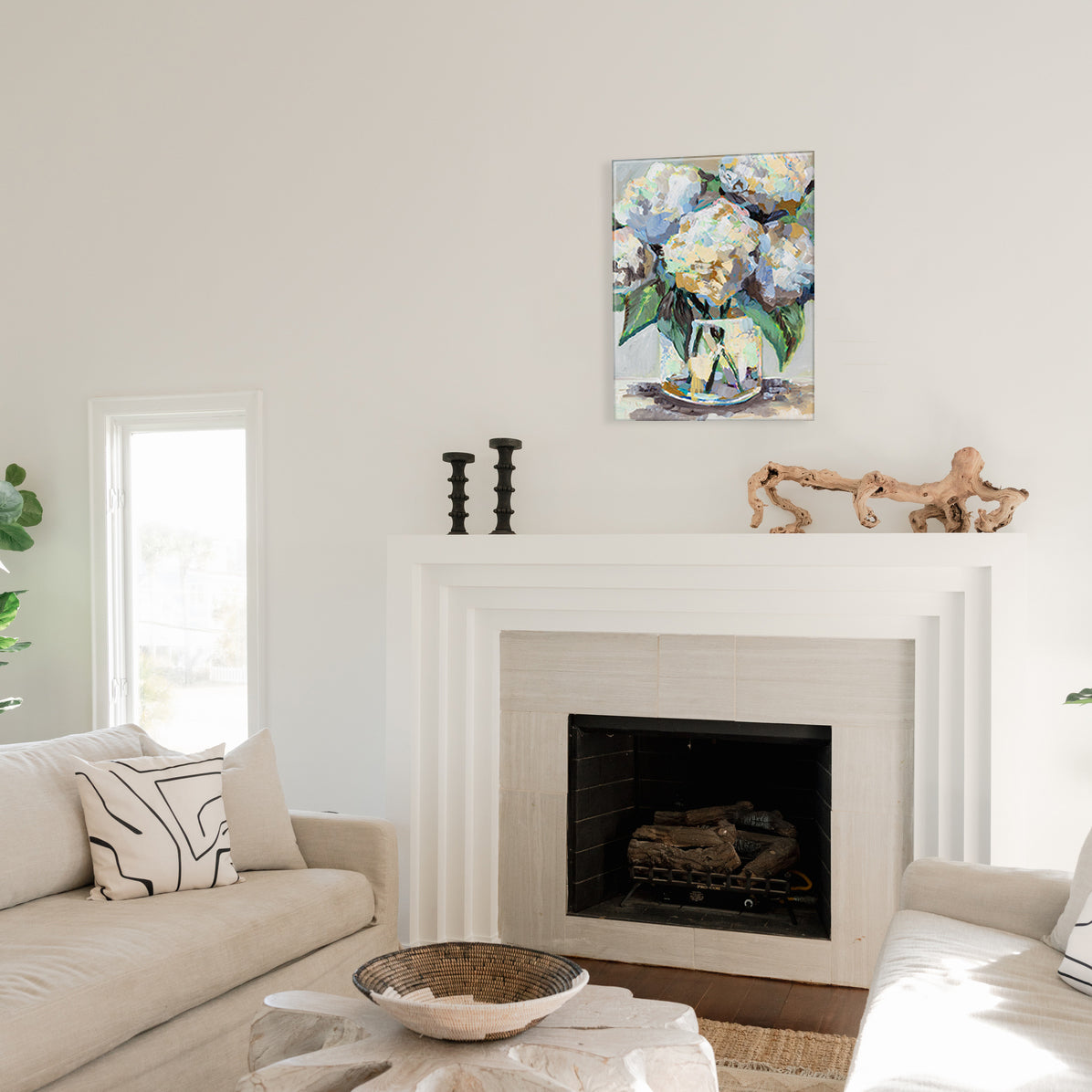 Glass print of living room with a fireplace, glass print of hydrangea artwork above it, and a couch.