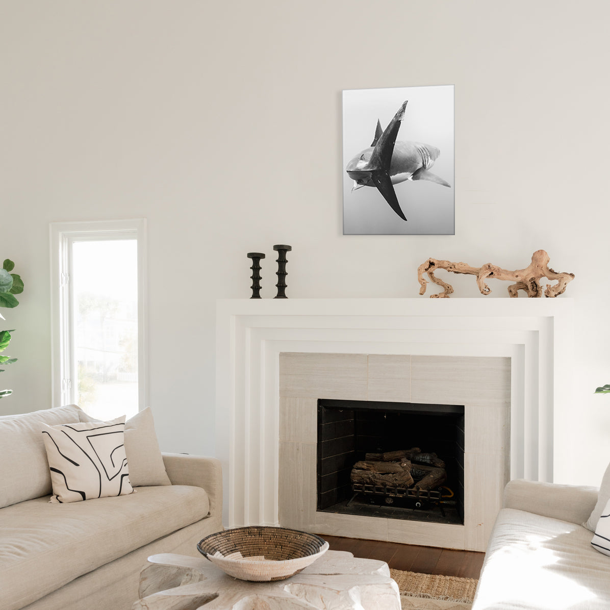 Living room with a fireplace, sofa, and decorative items, and a glass print of a black and white shark photo above the mantel