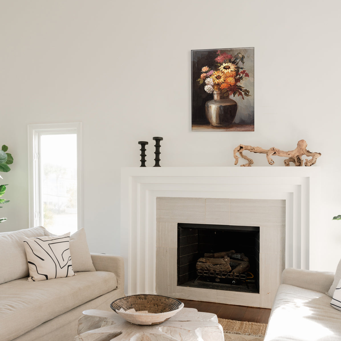 Living room with a fireplace, glass print of a floral painting above it, and candlesticks on the mantel.