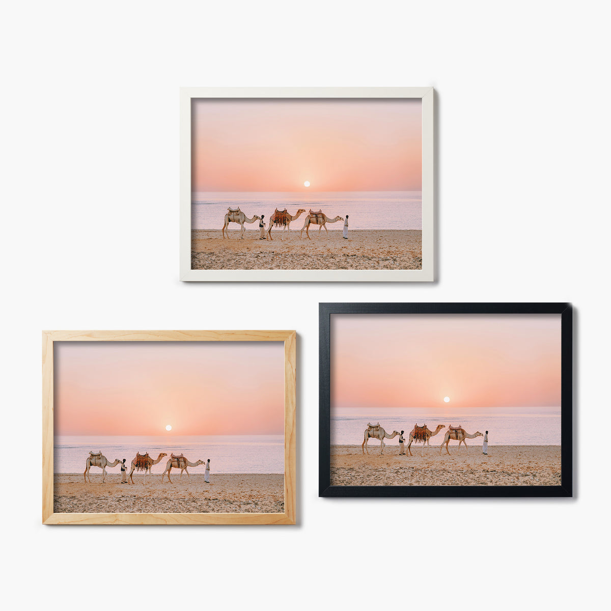 Three framed glass prints of a desert scene with camels and people against a sunset sky.