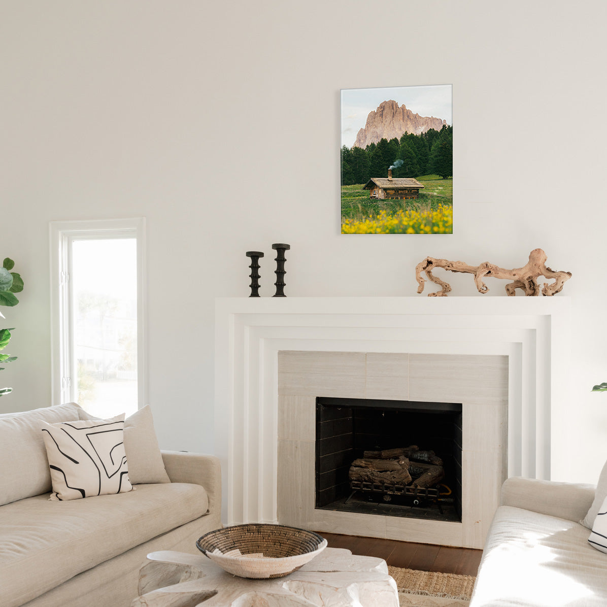 Living room with a fireplace, couch, and glass print wall art of a mountain and cabin.