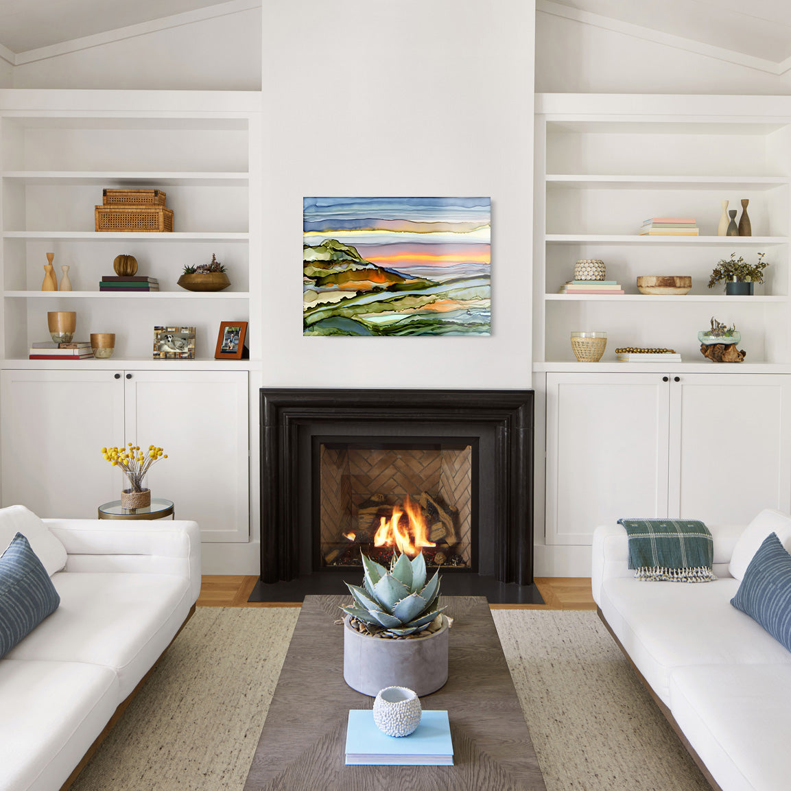 Modern living room with white walls, a fireplace, and a glass print of an abstract landscape above it