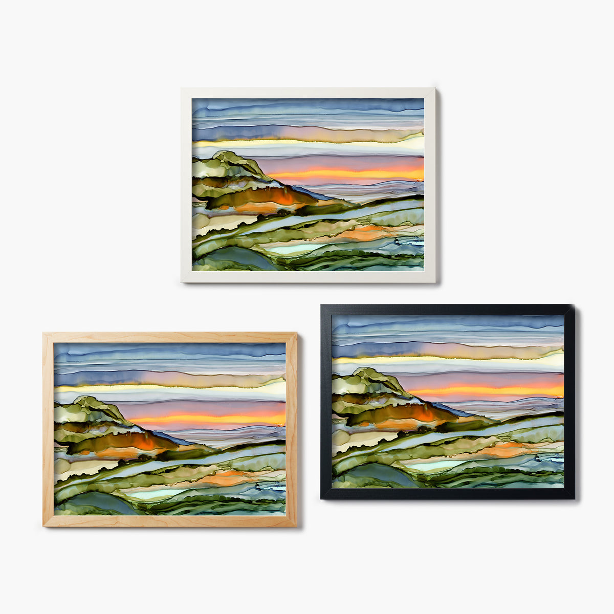 Three framed glass prints of abstract landscape paintings with different color frames on a white background