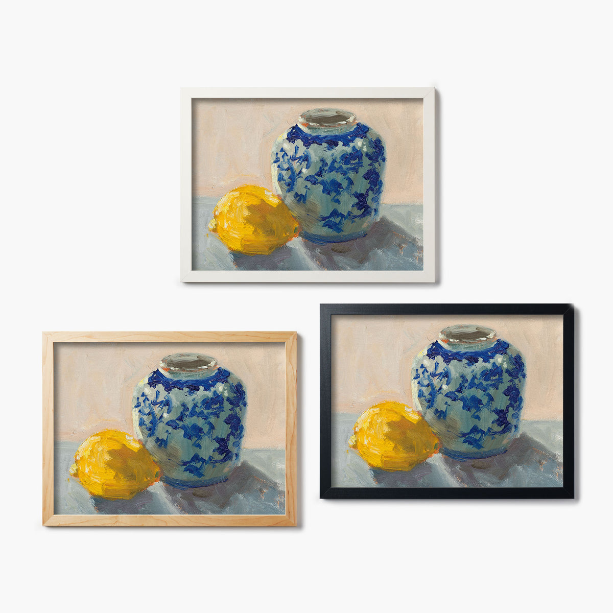 Three framed glass prints of paintings of a blue and white vase with a lemon on a white background