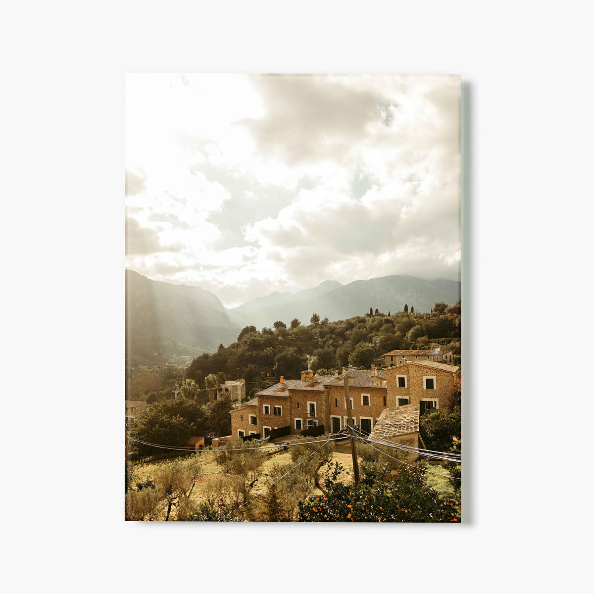 Glass print of a village with houses and mountains under a cloudy sky