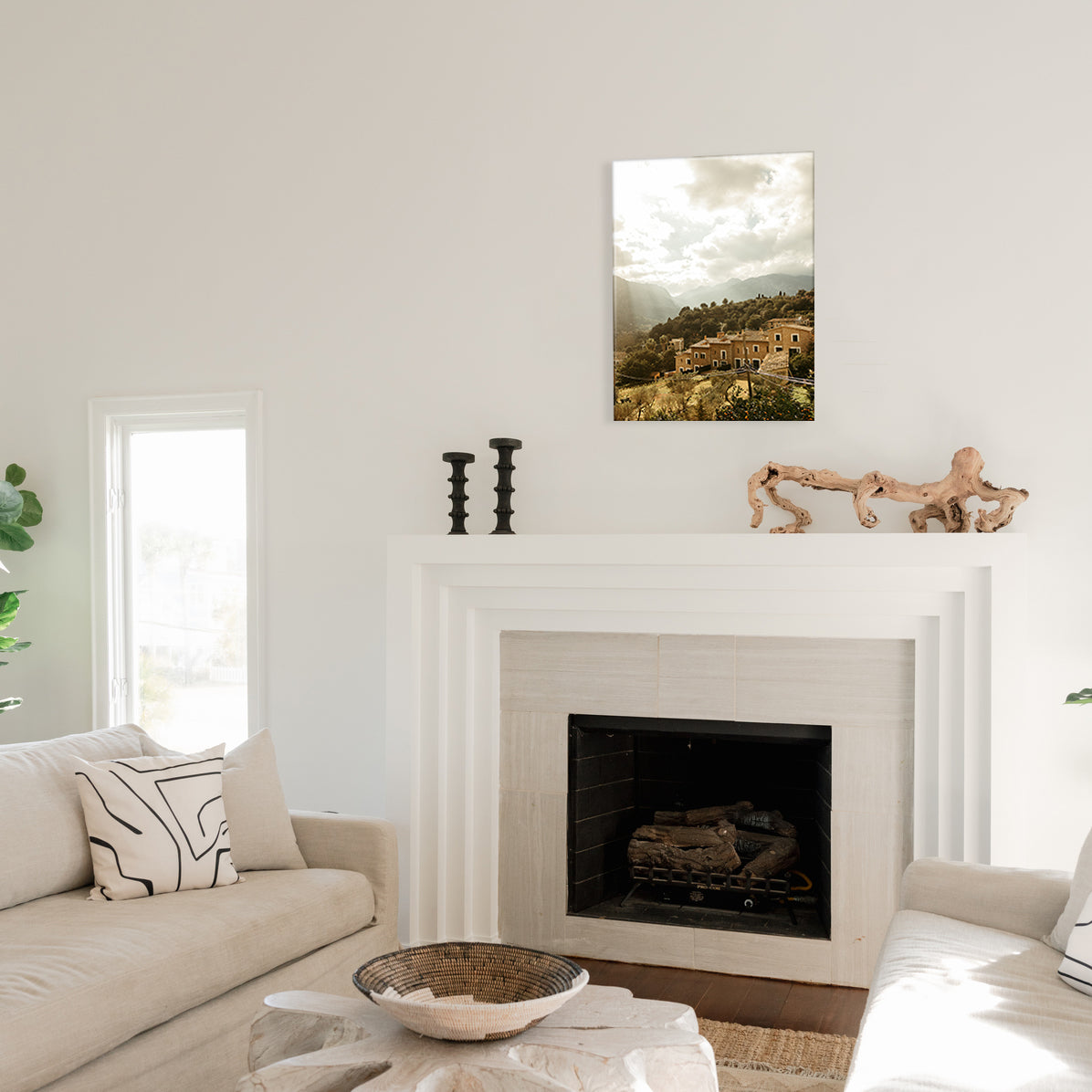Living room with a fireplace, a glass print of a mountain village, and a couch.