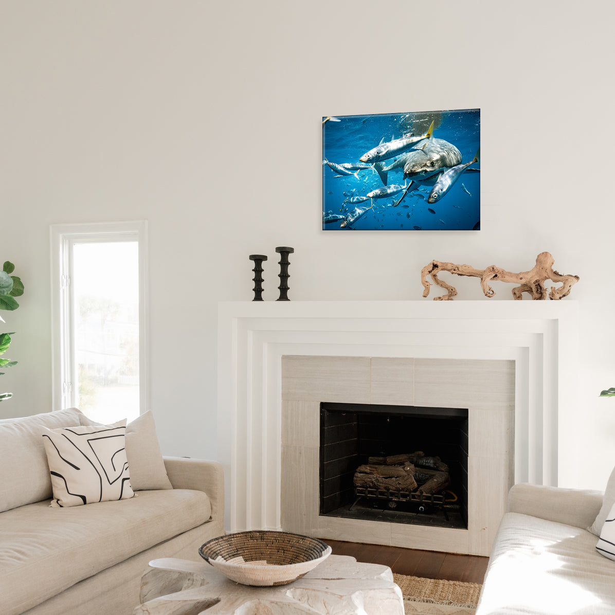 Living room with a fireplace and a glass print of a shark swimming amongst scattering fish on the wall.