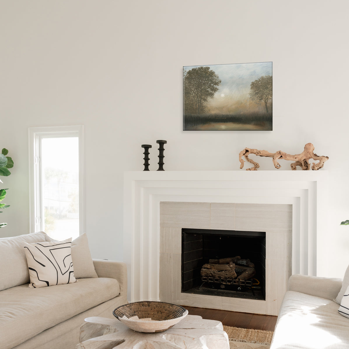 Living room with a fireplace, a glass print of a landscape painting above it, and decor items.
