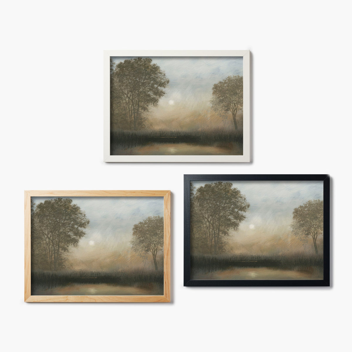 Three framed glass prints of a landscape painting of trees and a lake on a white background