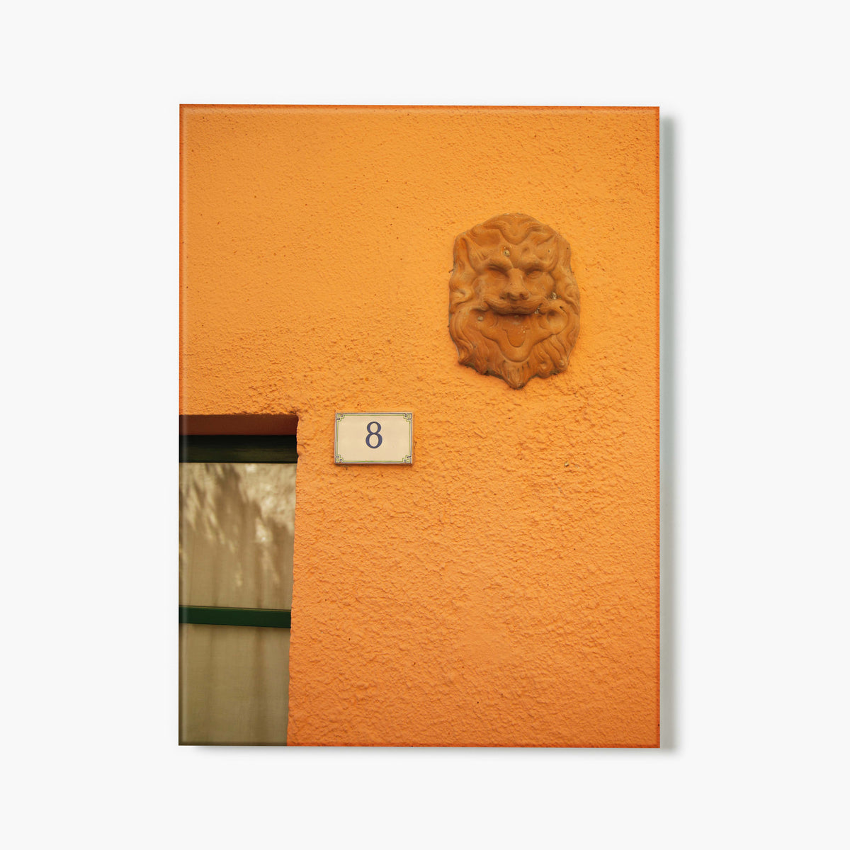Glass print of orange wall with a lion head sculpture and number 8 sign