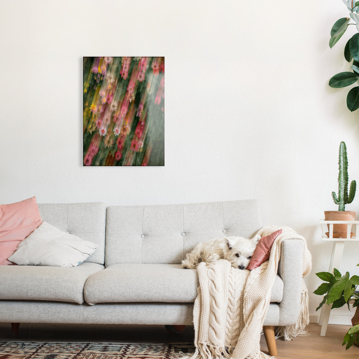 Living room with a gray sofa, a floral glass print on the wall, and a dog lying on the couch.
