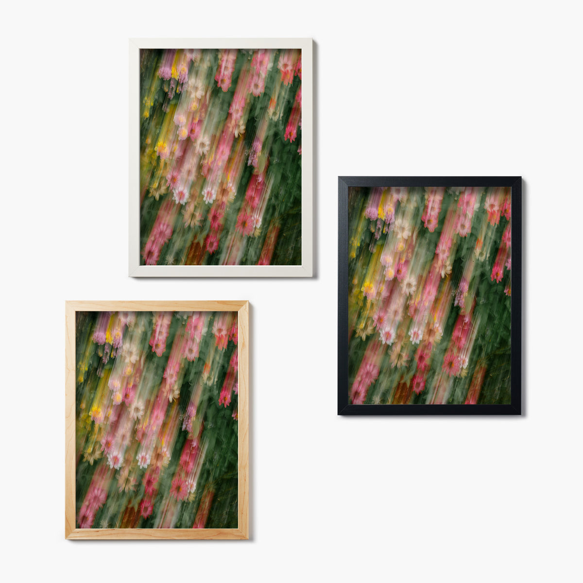 Set of three framed glass prints of artistically blurred flowers on a white background