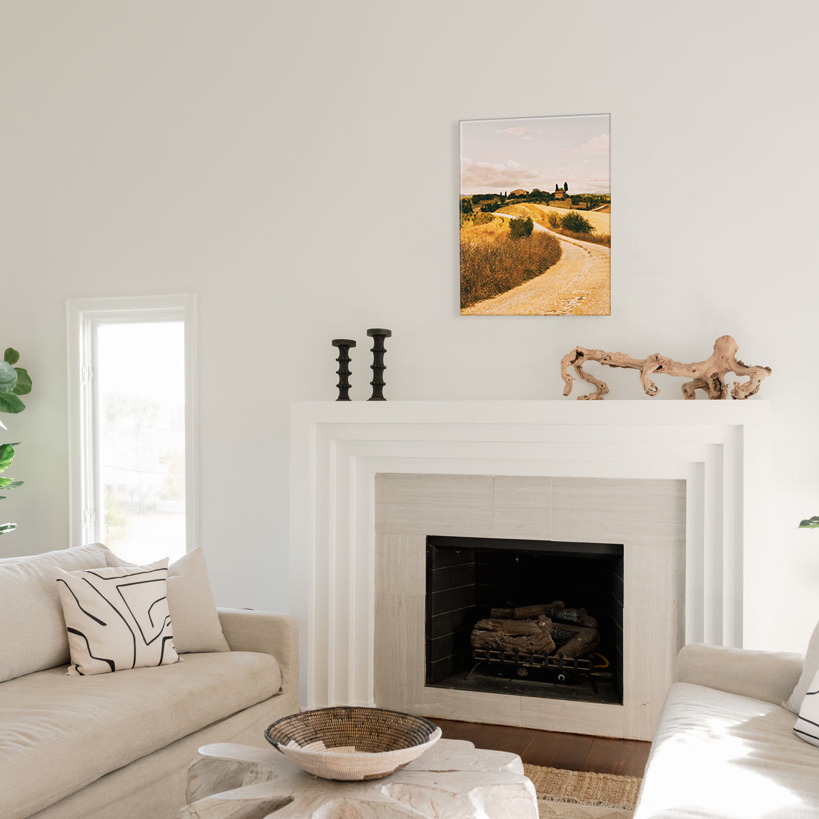 Living room with a fireplace, a glass print of a winding road landscape, and a couch.