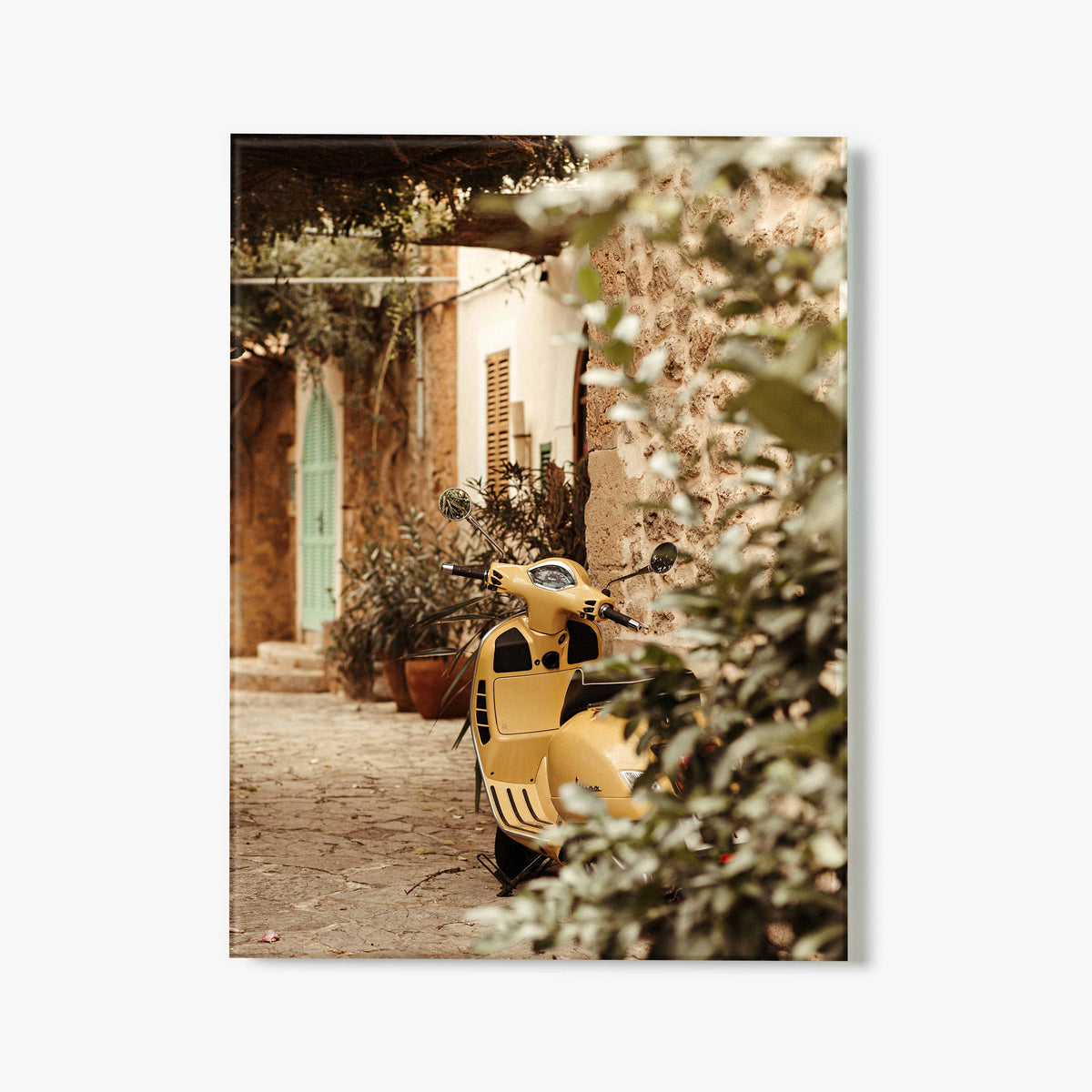 Yellow scooter parked in a quaint outdoor setting with a building and greenery.