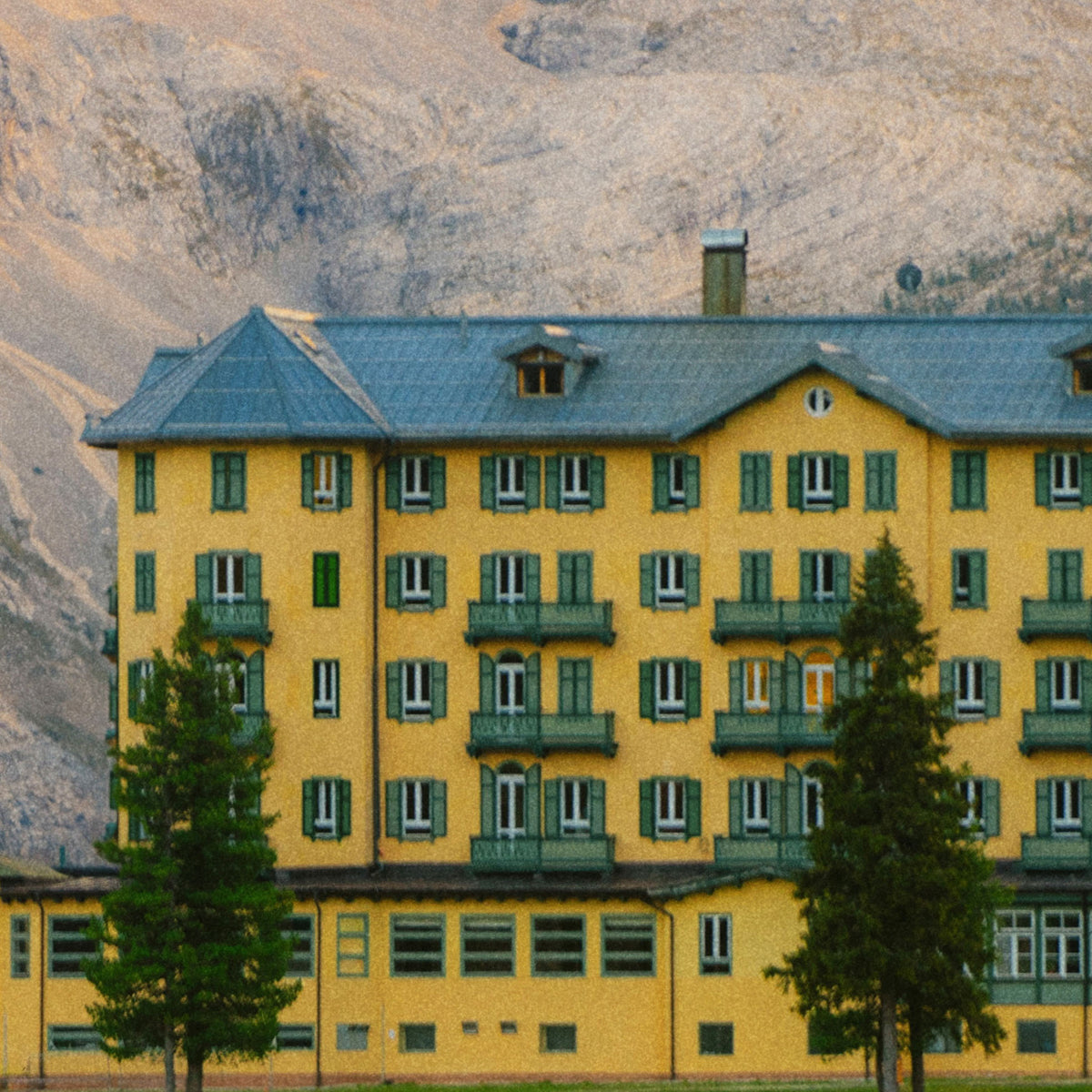 Close-up of yellow building with green shutters against a mountainous background